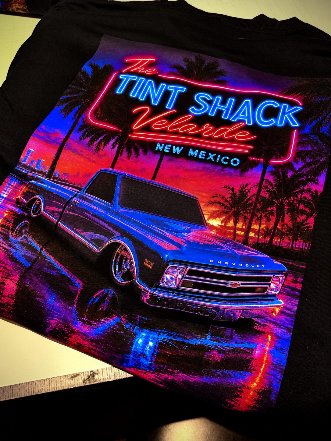 The Tint Shack Velarde neon artwork with a blue Chevrolet truck printed on a black shirt